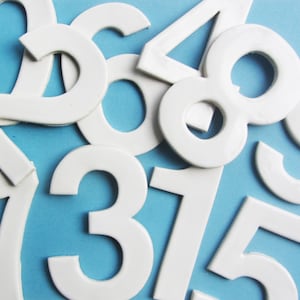 Pode incluir: Números de espuma branca de 1 a 9 sobre um fundo azul claro.