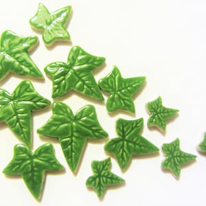 May include: A collection of green ceramic ivy leaves of various sizes. The leaves are arranged in a cluster on a white background.