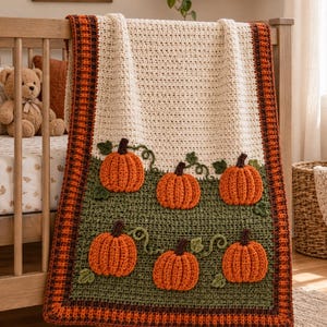Può includere: Una coperta rettangolare all'uncinetto con una sezione superiore color crema e una sezione inferiore verde oliva scuro decorata con sei zucche arancioni testurizzate con steli marroni e viticci verdi, bordata da un motivo a quadri marrone e arancione.