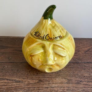 May include: A ceramic onion-shaped jar with a green top and a sad face. The jar is labelled "Pickled Onions".
