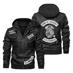 Op de afbeelding: Zwarte leren jas met afneembare capuchon. Voorzien van patches met de tekst "PRESIDENT MEN OF MAYHEM", "REDWOOD ORIGINAL" en "SAMCRO". De achterkant van de jas toont een afbeelding van een zeisdrager en de woorden "SONS OF ANARCHY CALIFORNIA MC".