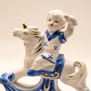 3 Porcelain White and Blue Figures, a girl and boy on a unicorn, standing figure.