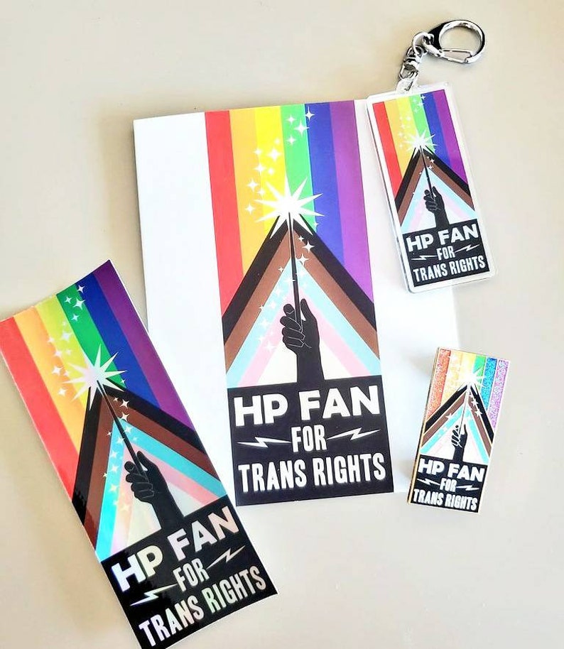 May include: A set of four stickers and a keychain featuring a rainbow flag with a black hand holding a wand with a spark at the top. The text on the stickers and keychain reads "HP FAN FOR TRANS RIGHTS".