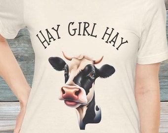 May include: A white t-shirt with a black and white cow illustration and the text "HAY GIRL HAY" printed on the front.