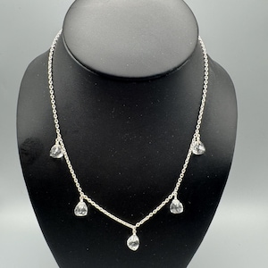 Puede incluir: Un collar de cadena de plata con cinco cristales transparentes en forma de lágrima que cuelgan.