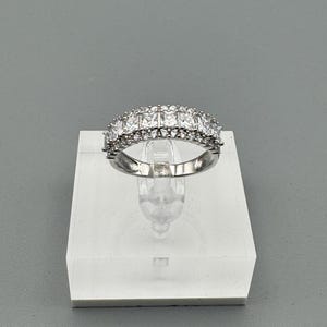 May include: A silver ring with a double row of clear square-shaped stones.