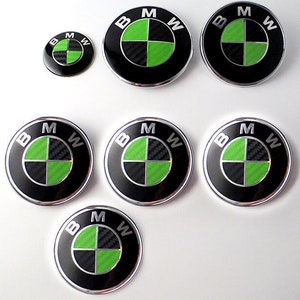 Könnte beinhalten: Satz von sieben schwarzen und grünen BMW-Autoemblemen mit einem Karbonfaser-Muster. Die Embleme sind in verschiedenen Größen.