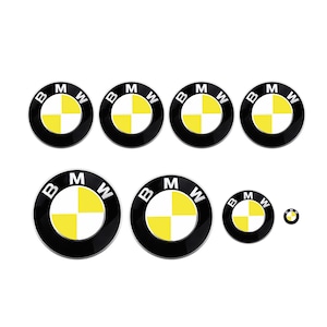May include: A set of eight BMW logo stickers in different sizes. Each sticker has a black circular border with the BMW letters and a yellow and white chequered centre. The stickers are displayed against a white background.