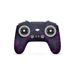 May include: A black drone controller featuring a topographic design in blue, pink, and purple. The controller has two joysticks, several buttons, and the DJI logo. The design is symmetrical and modern.