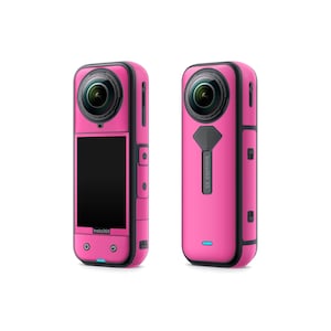 May include: Two pink Insta360 X3 cameras are shown. The cameras have a black lens, a black screen, and black accents. The Insta360 logo is visible on the front of one camera. The other camera has the text "Insta360 X3" on the back.