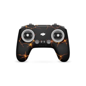 May include: Black drone controller with a cracked orange design. The controller has two control sticks, buttons, and a power button. The DJI logo is visible on the front.
