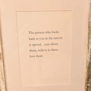 Op de afbeelding: Een ingelijste print met een witte passe-partout en een verweerde wit en goudkleurige lijst. De tekst op de print luidt: "De persoon die naar je terugkijkt in de spiegel is speciaal... zorg voor hen, geloof in hen, houd van hen."
