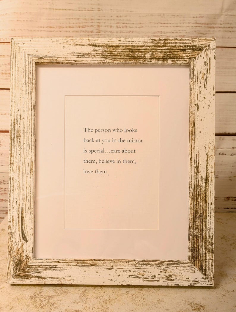 May include: A framed print with a white distressed wooden frame. The print has a white background with the text: "The person who looks back at you in the mirror is special...care about them, believe in them, love them."