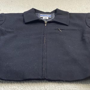 May include: A black wool jacket with a collar and a full-length zipper. The jacket has a small pocket on the chest and a label that reads "Pendleton". The jacket is a size M.
