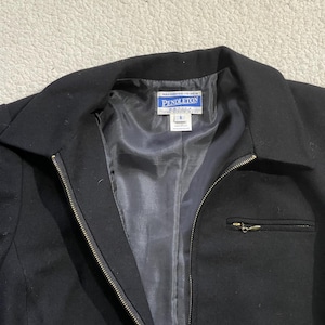 May include: Black jacket with a zipper closure and a small pocket on the chest. The jacket has a collar and a label that reads "PENDLETON". The jacket is size 8.