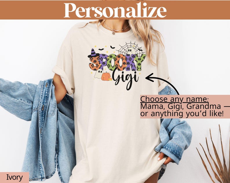 Może przedstawiać: Kremowa koszulka z halloweenową grafiką z napisem "Spooky Gigi". Projekt zawiera kapelusz czarownicy, pajęczynę, ducha i dynię. Tekst "Personalize" znajduje się na g&oacute;rze, a "Choose any name" znajduje się pod grafiką.