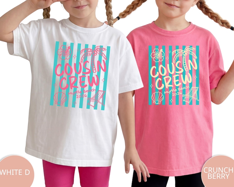Op de afbeelding: Een wit t-shirt en een roze t-shirt, elk met een afbeelding van verticale turquoise strepen, een hibiscusbloem, een palmboom, een schelp en een strandstoel. De tekst luidt COUSIN CREW Myrtle Beach 2026 in het roze en in het geel.