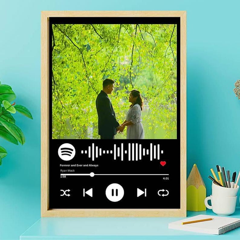 May include: Framed print featuring a couple holding hands in a park setting. The bottom portion displays a black music player interface with the song title "Forever and Ever and Always" and artist Ryan Mack.
