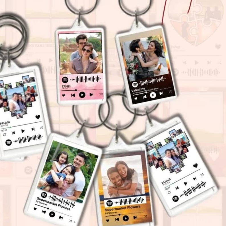 May include: A collection of personalized keychains featuring photos and Spotify-style music visualizations. Each keychain displays a different image, with song details and playback controls. The keychains are rectangular with rounded corners and silver key rings.