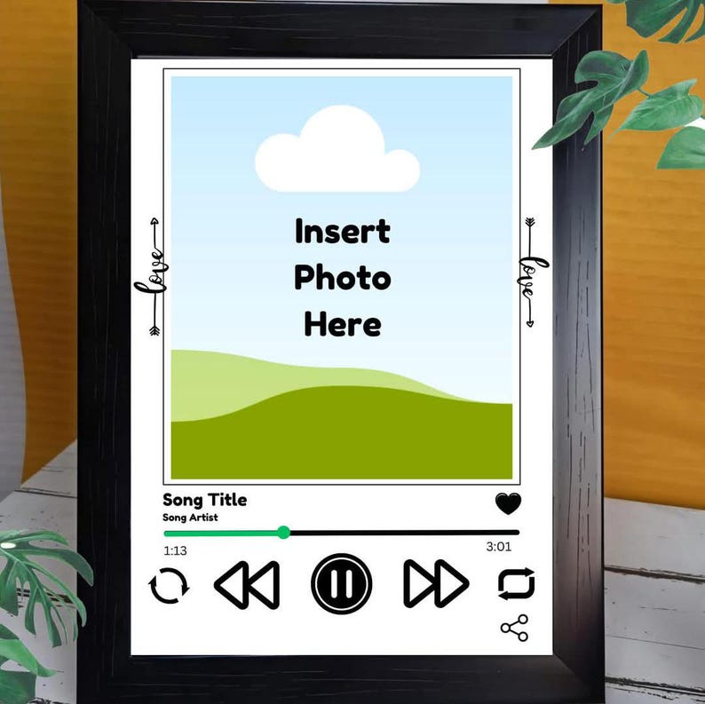 May include: A framed print with a black border. The print features a landscape scene with a blue sky and green hills, and the words "Insert Photo Here." Below the image is a music player interface with song details and control icons.