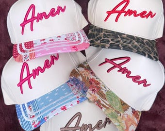 Può includere: Sei cappellini da baseball con calotte bianche e visiere a motivi vari. Cinque cappellini presentano la scritta Amen ricamata in rosa, mentre il cappellino in basso presenta la scritta Amen in marrone. Il cappellino in basso ha un adesivo D&Y.