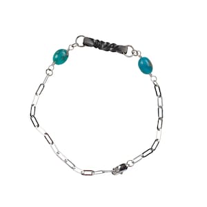 May include: A silver chain bracelet with a twisted black metal accent and two turquoise stones.
