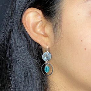 May include: Silver dangle earrings with a hammered silver disc and a turquoise stone in a silver circle.