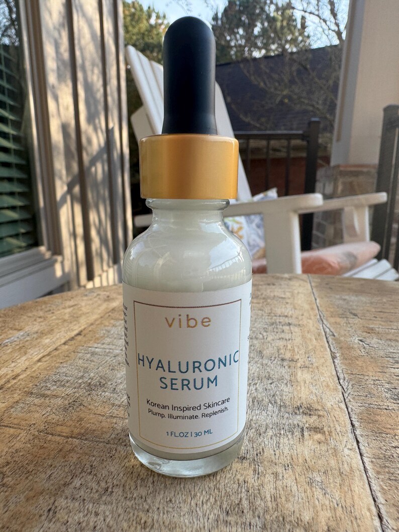 Peut inclure: Flacon en verre transparent de s&eacute;rum &agrave; l'acide hyaluronique avec compte-gouttes noir et bouchon dor&eacute;. L'&eacute;tiquette indique "vibe HYALURONIC SERUM Korean Inspired Skincare". Le flacon contient 30 ml de s&eacute;rum.