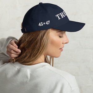 May include: A navy blue baseball cap with white embroidered text that reads "TRU 45*47".