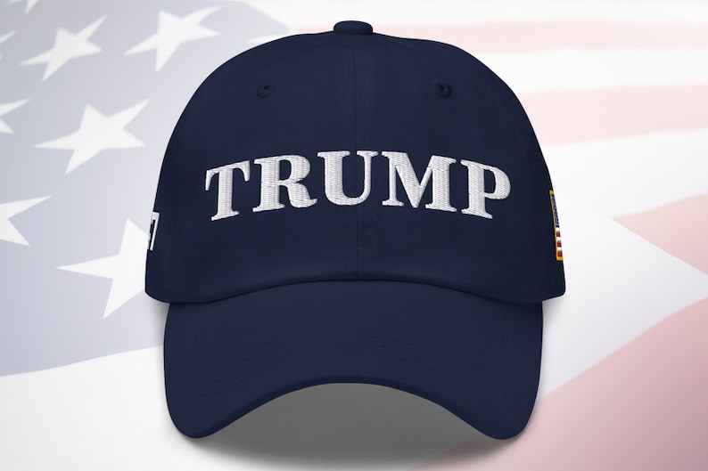 May include: A navy blue baseball cap with a white embroidered "TRUMP" on the front and a small American flag patch on the side.