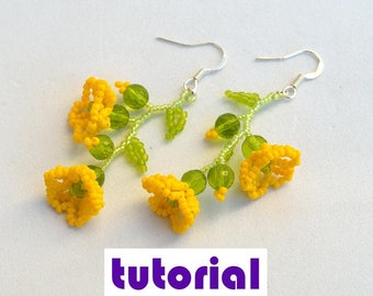 May include: A pair of handmade beaded earrings featuring yellow flower designs with green accents. The earrings have silver-colored hooks and are set against a white background. The word "tutorial" is at the bottom of the image.
