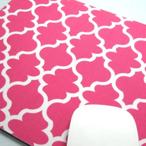 May include: Pink and white geometric patterned mouse pad. The pattern is a repeating design of quatrefoils.