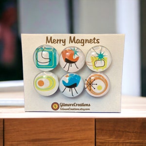 May include: Set of six round refrigerator magnets featuring mid-century modern designs in shades of blue, orange, yellow, and white. The magnets are labeled "Merry Magnets" and include the text "GilmoreCreations GilmoreCreations.etsy.com".