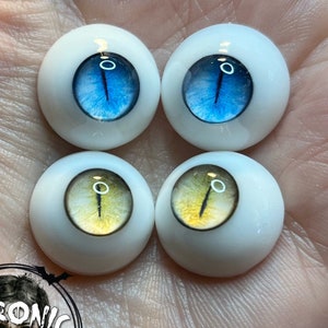 Puede incluir: Cuatro pares de ojos de muñeca, dos azules y dos amarillos, con pupilas negras y un iris blanco. Los ojos están sobre un fondo blanco.