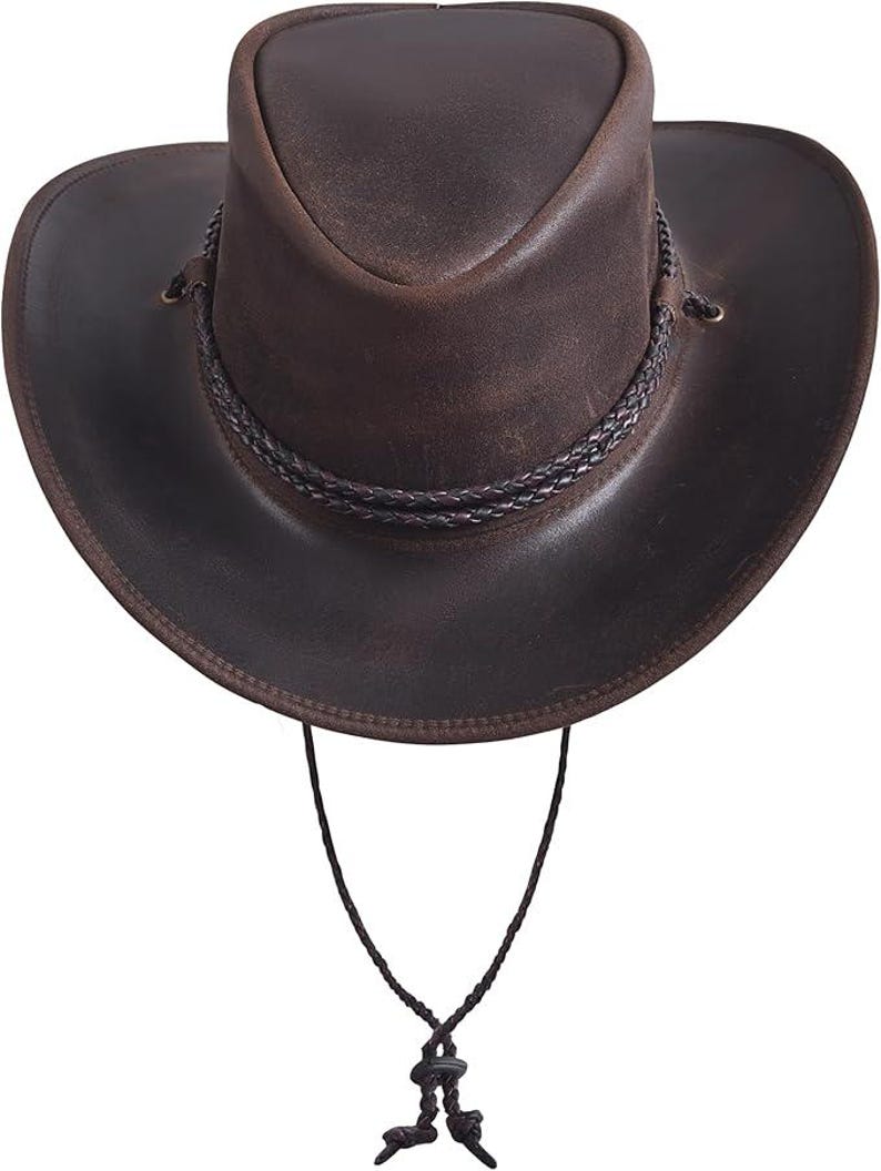 Puede incluir: Sombrero de vaquero de cuero marr&oacute;n con una banda trenzada alrededor de la corona y una correa para la barbilla. El sombrero tiene un ala ancha y un estilo occidental cl&aacute;sico. El sombrero est&aacute; hecho de cuero envejecido.