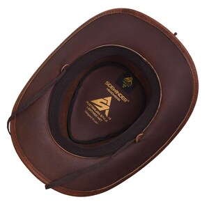May include: A brown leather cowboy hat, viewed from the inside, with a dark brown interior and a black band. The hat features the text "Sidewinder Headwear" and "Australian Style Leather Hat".