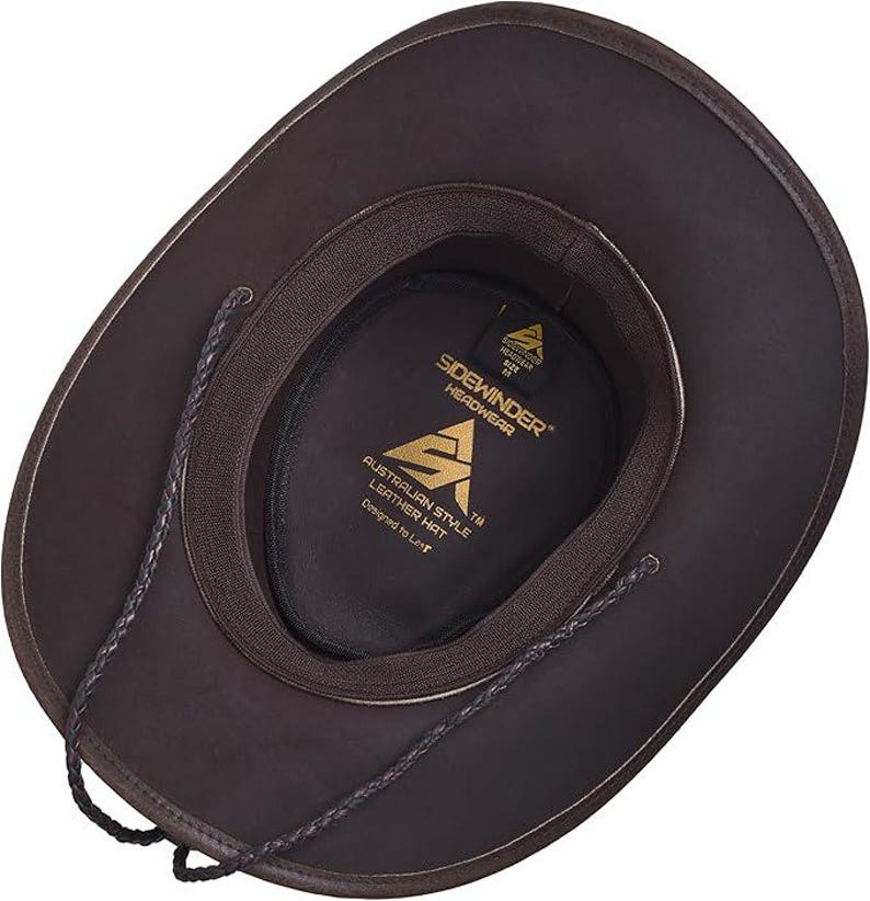 Puede incluir: Sombrero de vaquero de cuero marr&oacute;n con ala ancha y barboquejo de cuero trenzado. El interior del sombrero presenta un forro marr&oacute;n oscuro y una etiqueta que dice "Sidewinder Headwear". El sombrero es de estilo australiano.