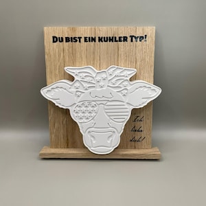 Könnte beinhalten: Holz Schild mit einer weißen Kuhkopf-Aussparung, die eine Sonnenbrille und ein Bandana mit Sternen und Streifen trägt. Das Schild sagt "Du bist ein cooler Typ!" und "Ich liebe dich!"