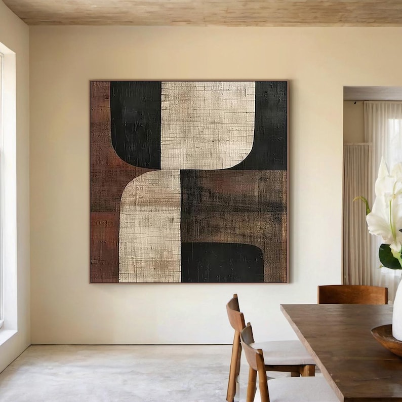 May include: Abstract geometric painting with black, white, brown, and red shapes on a textured canvas. The painting is hung on a beige wall in a modern interior.