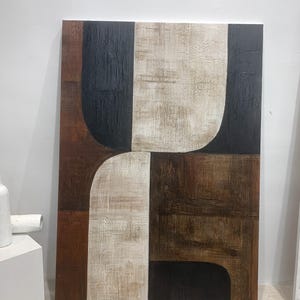 May include: Abstract art painting with geometric shapes in black, brown, and white on a canvas.