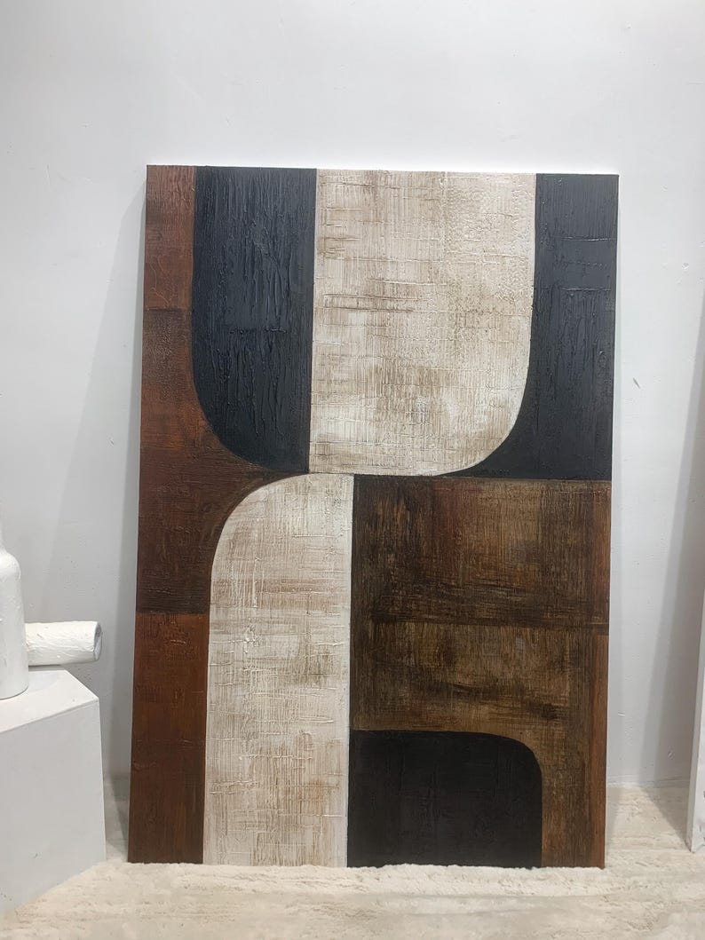 May include: Abstract art painting with geometric shapes in black, brown, and white on a canvas.
