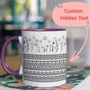 Könnte beinhalten: Weiße Keramiktasse mit lila Griff und Innenraum. Die Tasse hat oben ein schwarz-weißes Blumendesign und in der Mitte geometrische Muster. Der Text "Custom hidden Text" wird in einer rosa Sprechblase angezeigt.