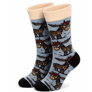 May include: A pair of crew socks featuring a light blue base with a repeating pattern of brown donkeys with red hair and grumpy expressions. The socks have a cream-coloured ribbed cuff at the top and a solid black heel and toe section.