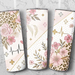May include: Three white insulated tumblers with floral and leopard print designs. Each tumbler features pink flowers, gold accents, and a heartbeat line. Cross symbols are also present on the tumblers.