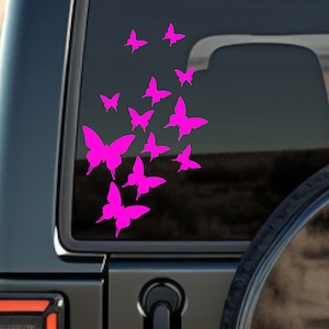 May include: A pink butterfly decal with multiple butterflies in a cluster, applied to the rear window of a black SUV.