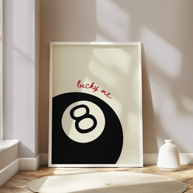 May include: A white framed print with a black and white illustration of a pool ball with the number 8 on it. The text "lucky me." is written in red cursive above the ball.