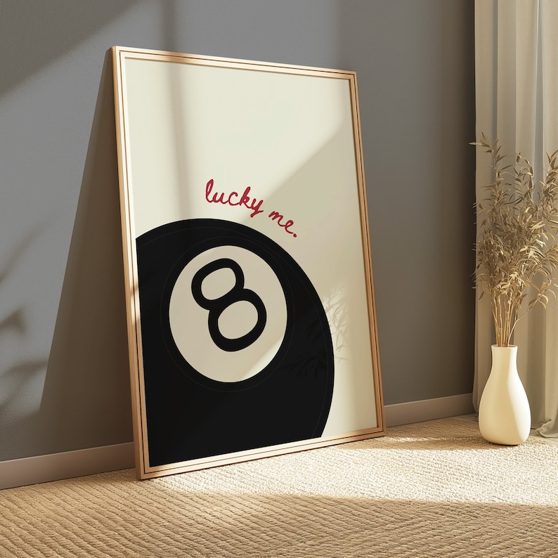 May include: A framed print with a black and white illustration of a pool ball with the number 8 on it. The text "lucky me." is written in red above the ball.