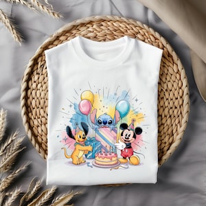 May include: White t-shirt with a colorful birthday scene featuring Stitch, Mickey Mouse, and a dog holding a gift. The scene includes balloons, a cake with candles, and a rainbow-colored gift box.