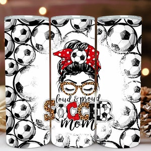 May include: Three white insulated tumblers with a soccer theme. The central tumbler features a woman with a red polka dot headband, leopard print glasses, and the text "loud & proud SOCCER mom". The other tumblers are decorated with soccer balls.