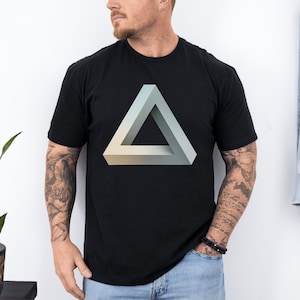 May include: Black t-shirt featuring a 3D impossible triangle graphic in shades of blue, gray, and beige. The geometric design is centered on the front of the shirt. The shirt is made of a soft material.